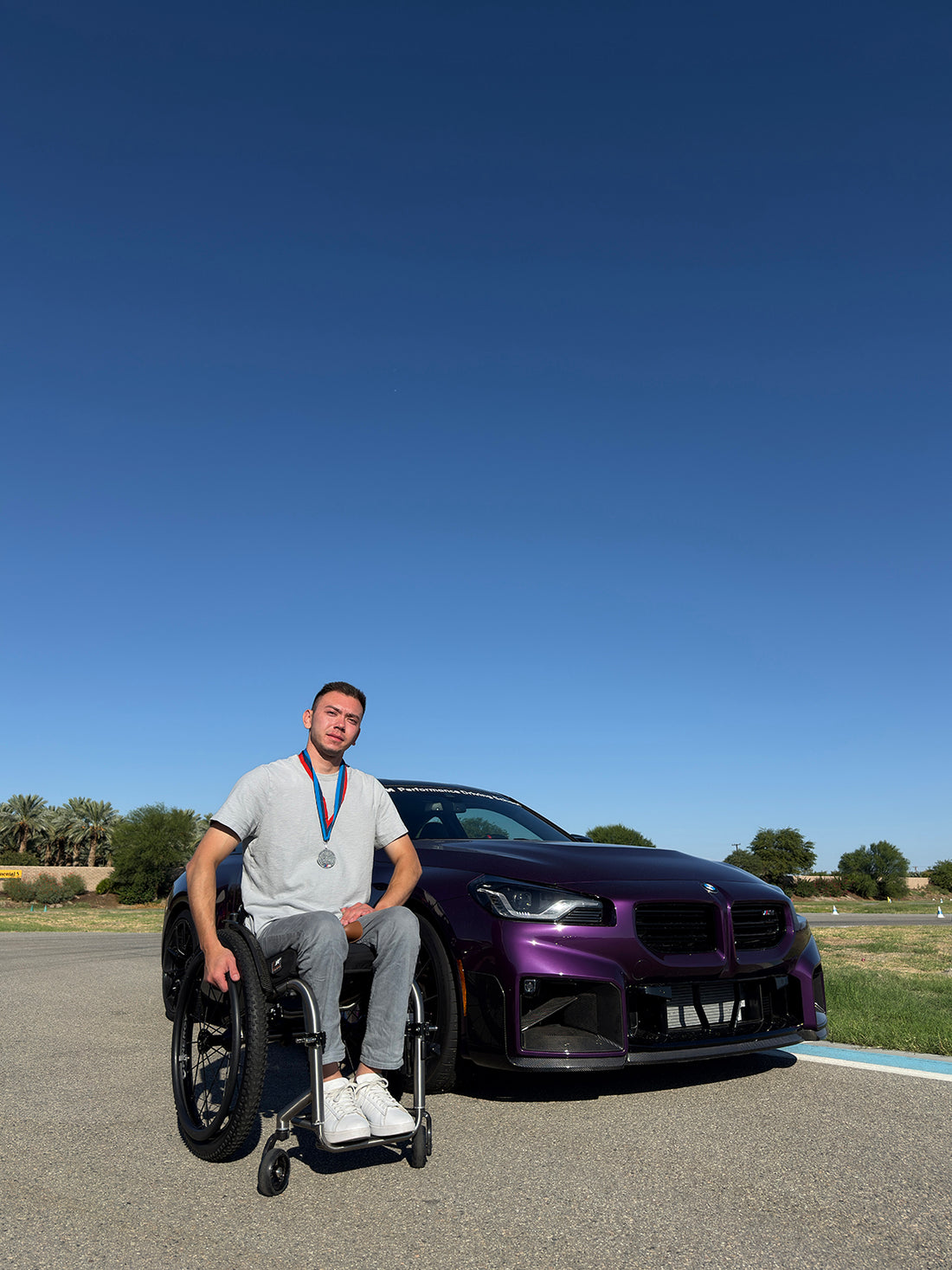 Darkhan with his wheelchair beside his purple BMW